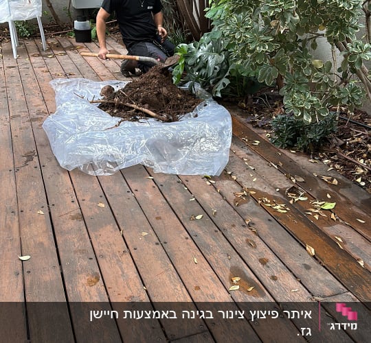 אדם חופר באדמה עם את חפירה על דק עץ